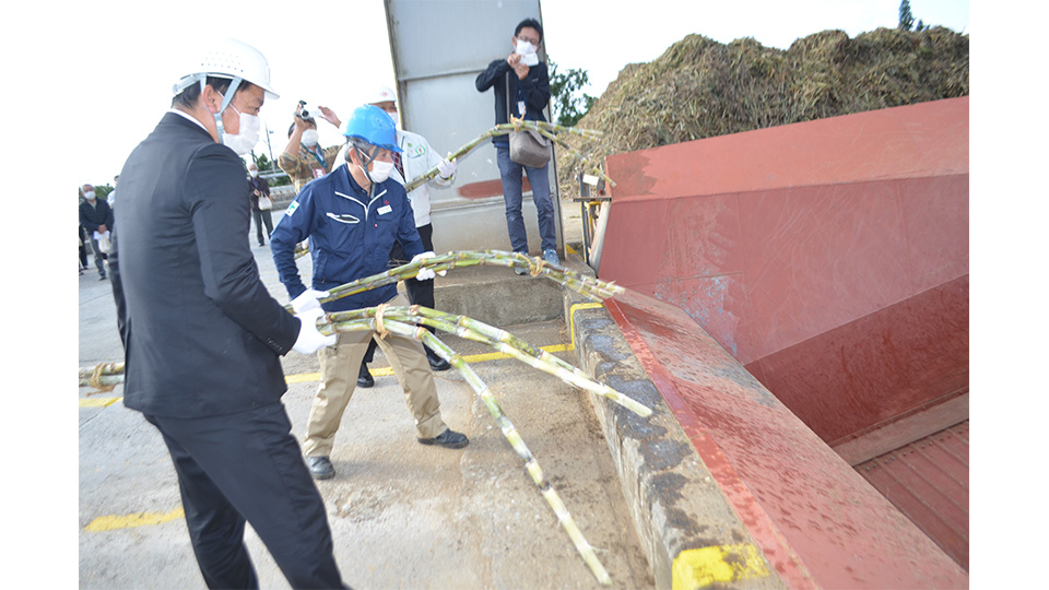 ヤードにキビを投げ込む松林社長、中山市長（手前）ら関係者＝３日午後、石垣島製糖