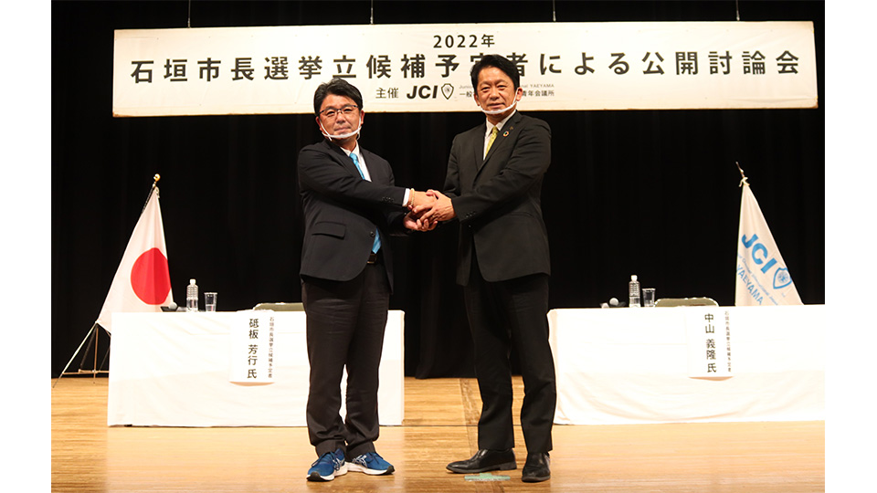 公開討論会後、握手する砥板氏と中山氏＝４日夜、石垣市民会館大ホール